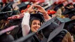一个毕业生微笑着举起他们的手，形成一个心形